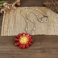 Dettaglio della collana con pendente a margherita rossa e perle su un tappetino rustico - Rosso - Trasparente