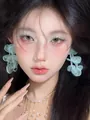 Macro view of mint green petal drop earrings worn by a model for summer beach vacation style - Fabric Petal Style