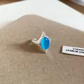 Detail eines silbernen Rings mit einem leuchtend blauen ovalen Katzenaugenstein - offener Ring / Blau