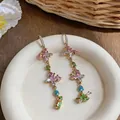 Detailed close-up of colorful butterfly zircon tassel earrings on a ceramic plate. - Ear Hook Style / Gold-Pink-Green