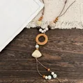 Close-up detail of ethnic style necklace featuring a ceramic shell and wooden ring accents - Coffee-White