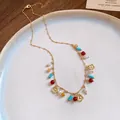 Detailed view of bohemian colorful beaded gold necklace with hollow flower pendants on a plate - Gold