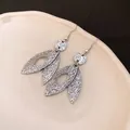 Close-up of vintage silver leaf drop earrings with detailed metal texture finish - Silver