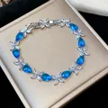 Detailed view of silver bracelet with blue water-drop zircons and white flower accents - Silver-Blue
