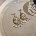Detailed view of French palace style teardrop earrings with crystals and bead tassels - Clear