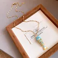 Close-up of a blue enamel fish pendant on a dainty gold stainless steel chain. - Necklace / Gold-Blue