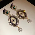 Detailed view of vintage evil eye drop earrings with shimmering rhinestones and pearls - Silver Earring Post Style / Gold-Multicolor