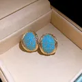 Detail macro view of vintage oval stud earrings with turquoise stones in gold setting - Gold-Blue