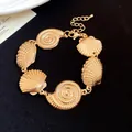 Detailed macro view of vintage gold metallic seashell bracelet with nautilus charms - Bracelet / Gold