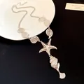 Close-up of vintage silver seashell and starfish necklace with pleated texture detail - Necklace / Silver