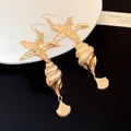 Detailed view of gold starfish and conch shell drop earrings with metallic texture - Earring Hooks / Gold