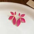 Close-up detail view of pink enamel flower earrings with gold edges on a white tray - Pink