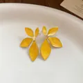 Close-up detail of vintage yellow enamel floral stud earrings with gold plating. - Yellow