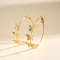 Detailed close-up view of golden metal hoop earrings with delicate butterfly charms - Butterfly Geometric Hoop / Gold