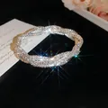 Nahaufnahme eines funkelnden, mit Strass besetzten, geflochtenen Armbands auf Samt - Silber-Weiß