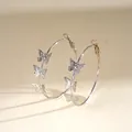 Detailed side view of silver hoop earrings featuring delicate butterfly charms on a cream base - Butterfly Geometric Hoop / Silver