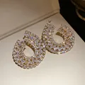 Détail macro de boucles d'oreilles gouttes géométriques avec zircons étincelants - Or