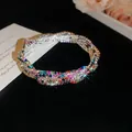 Nahaufnahme eines farbenfrohen geflochtenen Armbands mit funkelnden mehrfarbigen Steinen - Silber - Regenbogen