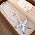 Detailed view of a white silky rope necklace featuring a large starfish pendant in a jewelry box - Necklace / White