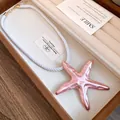 Detailed view of a pink starfish pendant necklace with a white silky rope chain - Necklace / Pink