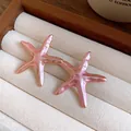 Detailed macro view of elegant pink starfish enamel earrings resting in a jewelry box - Earrings / Pink