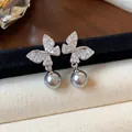 Close-up of dainty butterfly earrings with sparkling stones and grey pearl drops. - Silver