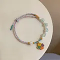 Close-up of handmade woven bracelet with pearls and colorful four-leaf clover charm - Four-Leaf Clover Style