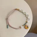 Detailed macro view of a handmade woven bracelet featuring white pearls and a colorful donut charm - Donut Style