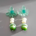 Primo piano di orecchini a fiore in resina verde con gocce di perle marmorizzate - Verde