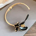 Gros plan d'un choker de style français vintage avec fleur en émail noir et strass brillants. - Or, Noir