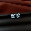 Macro view of light blue heart-shaped zircon flower stud earrings on dark leather background - Silver Earring Post - Silver - Blue
