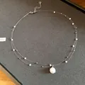 Vista detallada del collar de perlas de doble capa con un colgante brillante con pedrería. - Collar-Blanco