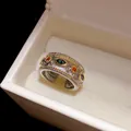 Dettaglio ravvicinato di un anello aperto stile corte vintage con zirconi verdi e arancioni - Versione Larga / Bicolore Oro e Argento