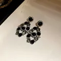 Detailed macro view of vintage palace style black gemstone and rhinestone drop earrings - Earrings Only (Silver Earring Post) / Black