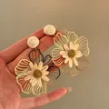Dettaglio di orecchini a fiore in paglia gialla intrecciata in stile vacanza a mano - Cachi