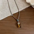 Dettaglio collana in corda intrecciata a mano con ciondolo pesce in pietra occhio di tigre e cuore - Collana / Marrone