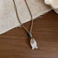 Dettaglio ciondolo a pesce in pietra con cuore inciso su cordino intrecciato - Collana / Bianco