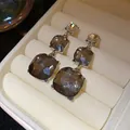 Macro view of tiered drop earrings with faceted smoky grey stones in a cream jewelry box - Silver Earring Post Style / Silver-Grey