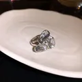 Vista dettagliata di un anello aperto in argento con tre gemme chiare brillanti - Grigio