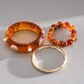 Macro detail of retro 3-piece jewelry set featuring amber resin bangle and gold bracelet - 3-Piece Bracelet Set / Gold Brown