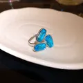 Primo piano di un anello regolabile in argento con tre cristalli sfaccettati blu. - Blu