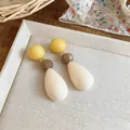 Close-up of colorful resin teardrop earrings with yellow and brown beads on a tray. - Three-Stage Spliced Style (HE32526) / Silver Earring Post-White