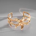 Detail view of a gold-toned cuff bracelet with intricate starfish-shaped designs - Gold