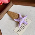 Close-up of a bohemian purple starfish hair clip with a central pearl on a straw base - Duckbill Hair Clips / Purple