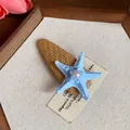 Close-up of a bohemian starfish hair clip featuring a pearl on a brown woven base - Duckbill Hair Clips / Blue