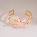 Elegant gold open cuff bracelet decorated with intricate pink enamel starfish charms - Pink