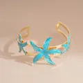 Elegant gold plated metal cuff bracelet featuring blue enamel starfish charms for women - Blue