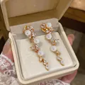 Dettaglio ravvicinato di eleganti orecchini a spiga dorati con perle e zirconi bianchi - Stile Nappina a Spiga di Grano (HE22397) / Oro