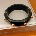 Dettaglio macro di un bracciale in resina vintage con borchie in metallo ambra - Bracciale(HB6151) / Nero