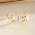 Gold cuff bracelet featuring white enamel starfish details in a minimalist design. - White